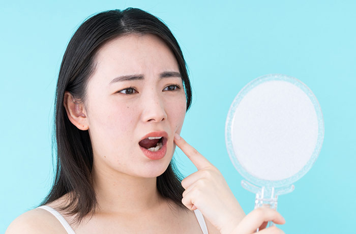 鏡で歯を見ている女性